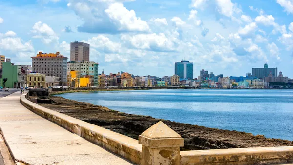 Vista del Malecón habanero con el mar al atardecer y el skyline de edificios coloniales al fondo.