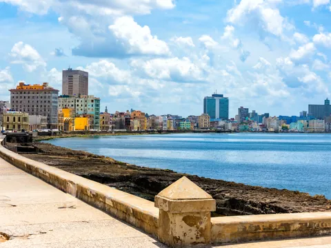 Vista del Malecón habanero con el mar al atardecer y el skyline de edificios coloniales al fondo.
