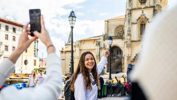 La guía señala la Catedral de Oviedo mientras le toman una foto.