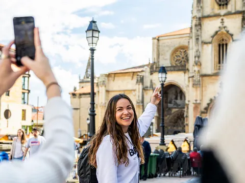 La guía señala la Catedral de Oviedo mientras le toman una foto.