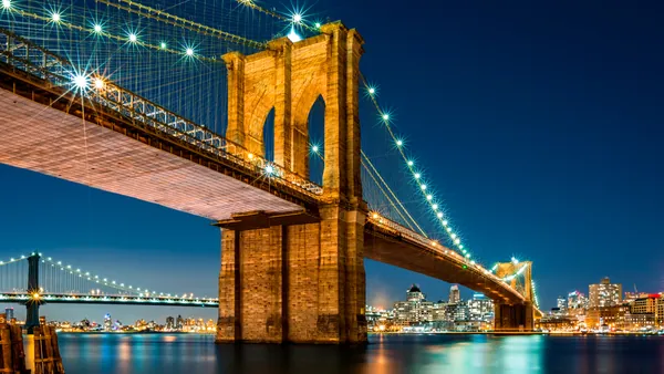 **Alt sugerido (≤80 caracteres):** Puente de Brooklyn iluminado de noche con el skyline de Nueva York
