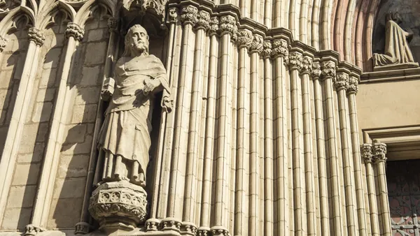 Escultura de figura religiosa en la fachada gótica de la Catedral de Santa María del Mar en Barcelona, con columnas ornamentadas.