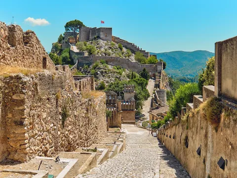 Castillo de Xàtiva sobre una colina con murallas y vistas a las montañas.