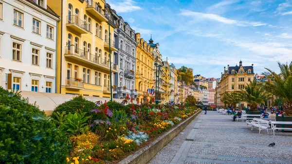 Fila de edificios coloridos y fuente de agua en la calle principal de Karlovy Vary.