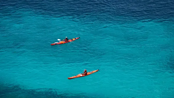 Kayaks rojos navegando por las aguas de Es Canutells, Menorca