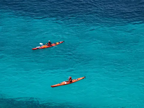 Kayaks rojos navegando por las aguas de Es Canutells, Menorca