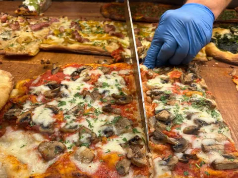 Pizzero italiano cortando una pizza con purchetta, otra de las recetas típicas que se prueban en este tour gastronómico por el barrio de Trastevere.