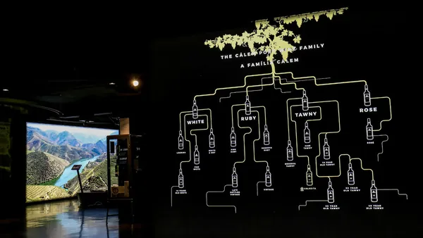 Panel iluminado con tipos de vino de Oporto en bodegas Cálem y pantalla del valle del Duero al fondo.