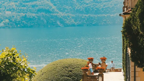 Terraza con flores y vista al Lago di Como frente a colinas frondosas