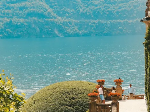 Terraza con flores y vista al Lago di Como frente a colinas frondosas