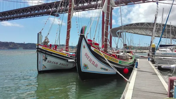 Moliceiros tradicionales junto al Puente 25 de Abril en un día soleado.