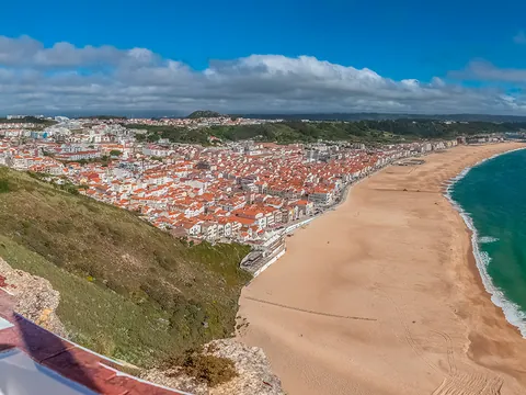 Vista panorámica de Nazaré con su extensa playa, el mar y las casas de tejados rojos.