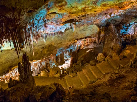 Escaleras de piedra entre estalactitas iluminadas en las Cuevas del Drach, Mallorca