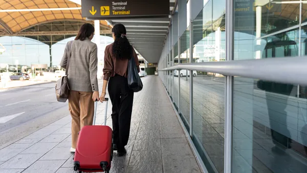 Dos chicas se bajan del avión con su maleta, para encontrarse con el personal de su traslado.
