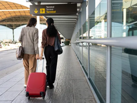 Dos chicas se bajan del avión con su maleta, para encontrarse con el personal de su traslado.