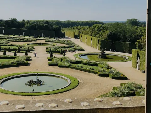 Vista del jardín exterior del Palacio de Versalles, con flores y arbustos bien cuidados en un entorno elegante.