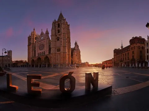 Catedral de León al amanecer, con el cartel de 'LEÓN' en primer plano, en la Plaza de la Regla, arquitectura gótica.