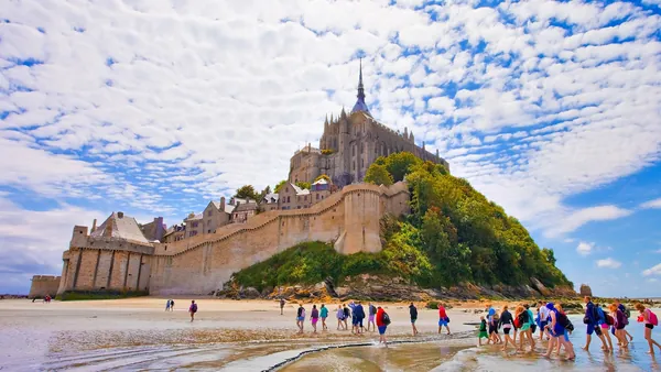 Claustro ajardinado y fachada gótica de la abadía del Mont Saint-Michel en Normandía, Francia.