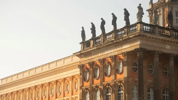 Detalle de la fachada del Nuevo Palacio (Neues Palais) en Potsdam, con ladrillo rojo, columnas y estatuas en el tejado.