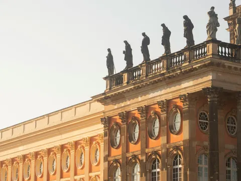 Detalle de la fachada del Nuevo Palacio (Neues Palais) en Potsdam, con ladrillo rojo, columnas y estatuas en el tejado.