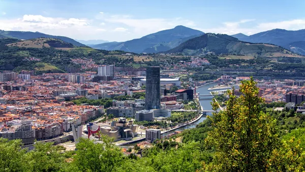 Vista panorámica de Bilbao con el Guggenheim, la torre Iberdrola y montañas al fondo.