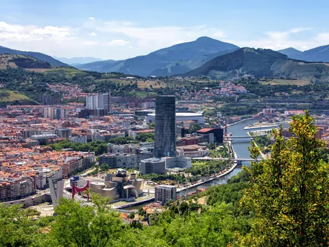 Vista panorámica de Bilbao con el Guggenheim, la torre Iberdrola y montañas al fondo.