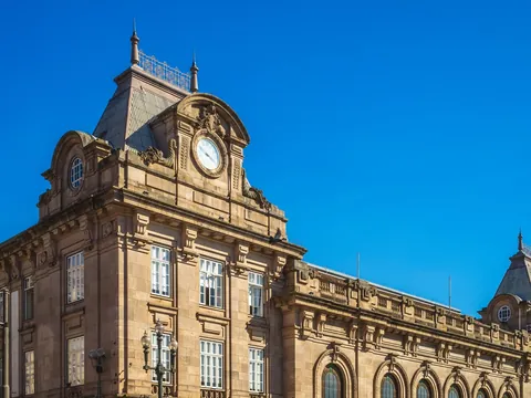 Fachada monumental de la estación São Bento en Oporto bajo cielo azul.