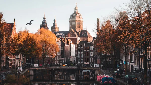 Canal de Ámsterdam con edificios reflejados en el agua y árboles otoñales