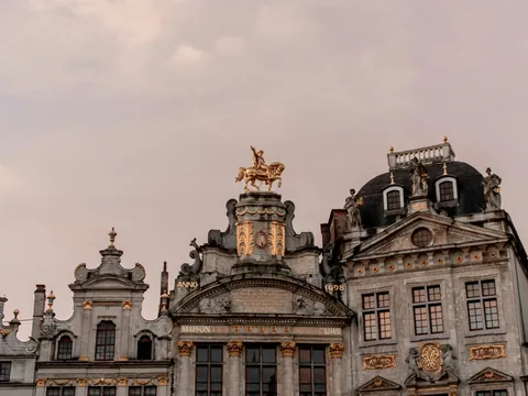 Edificio histórico en la Grand Place de Bruselas con estatua dorada de un caballo en la cima.