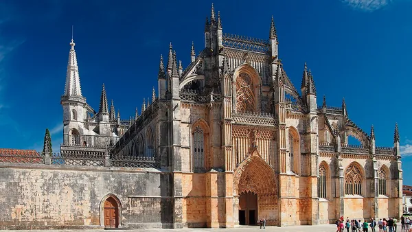 Fachada gótica del Monasterio de Batalha bajo un cielo azul despejado.