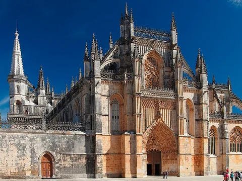 Fachada gótica del Monasterio de Batalha bajo un cielo azul despejado.