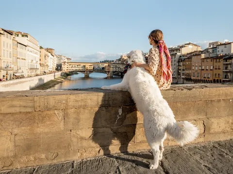 Una chica y su perro miran al río desde uno de los puentes de Florencia