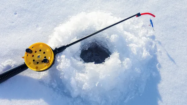 Primer plano de un agujero de hielo y caña de pescar en Rovaniemi, listo para una captura en el invierno ártico.