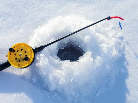 Primer plano de un agujero de hielo y caña de pescar en Rovaniemi, listo para una captura en el invierno ártico.