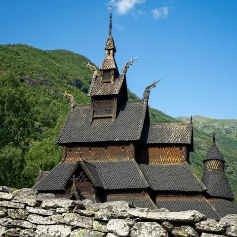 Iglesia de madera de Borgund en Noruega, arquitectura vikinga tradicional rodeada de montañas y naturaleza verde.