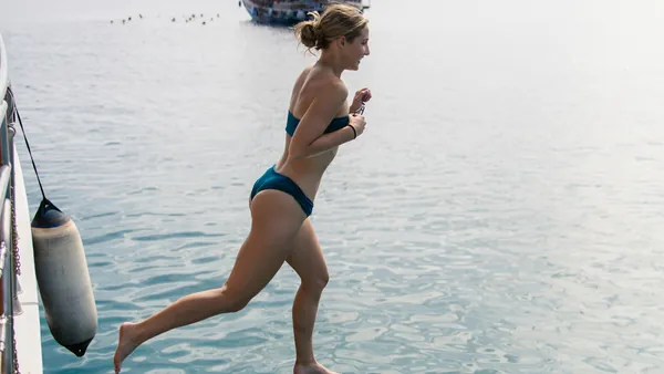 Chica saltando en el agua para darse un chapuzón en aguas tranquilas antes de la cena.