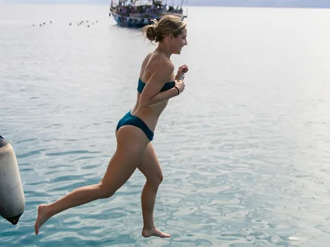 Chica saltando en el agua para darse un chapuzón en aguas tranquilas antes de la cena.