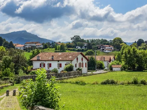 Casas blancas con contraventanas rojas entre prados verdes en Sare, en el País Vasco francés.