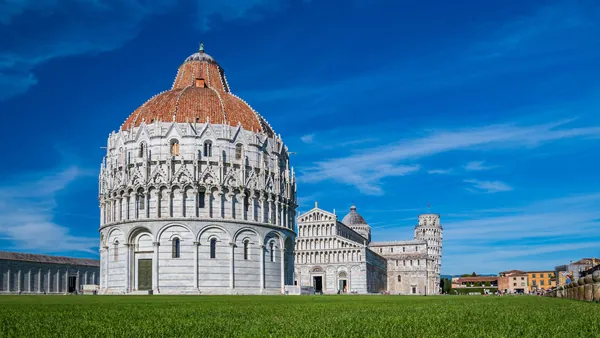 Vista del Baptisterio de Pisa, edificio circular de estilo románico y gótico, con cúpula y detalles arquitectónicos en mármol blanco, situado en la Piazza dei Miracoli.