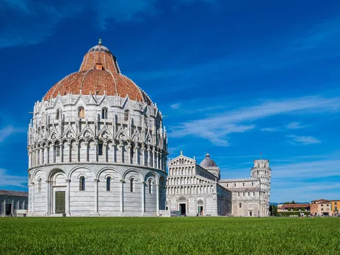 Vista del Baptisterio de Pisa, edificio circular de estilo románico y gótico, con cúpula y detalles arquitectónicos en mármol blanco, situado en la Piazza dei Miracoli.