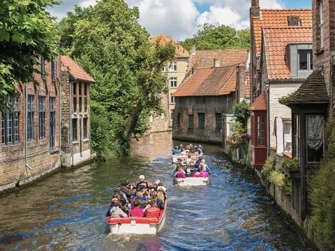 Grupo de turistas dando un paseo en barca por Brujas, Bélgica
