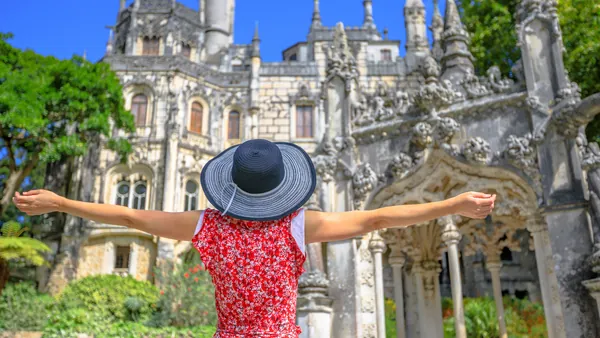 Turista con sombrero frente a la fachada decorada de la Quinta da Regaleira.