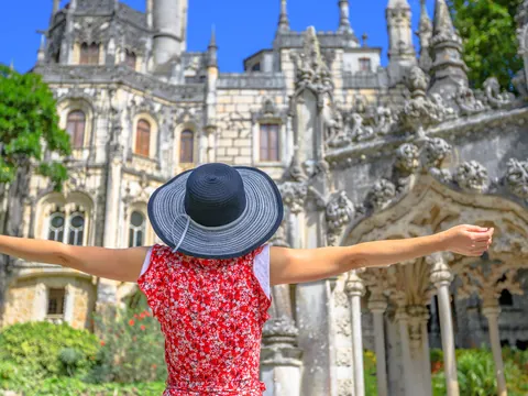 Turista con sombrero frente a la fachada decorada de la Quinta da Regaleira.
