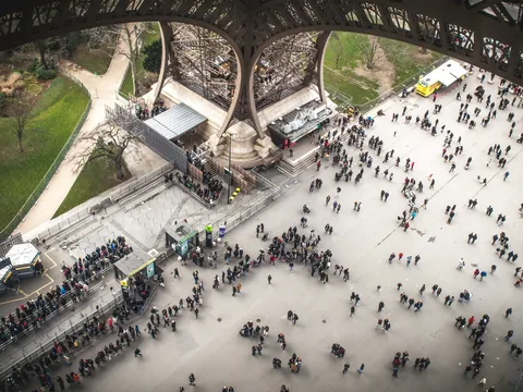 Explanada bajo la Torre Eiffel con visitantes en París, Francia