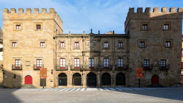 Fachada del histórico Palacio de Revillagigedo en Gijón, construido en piedra con torres y balcones frente a una plaza