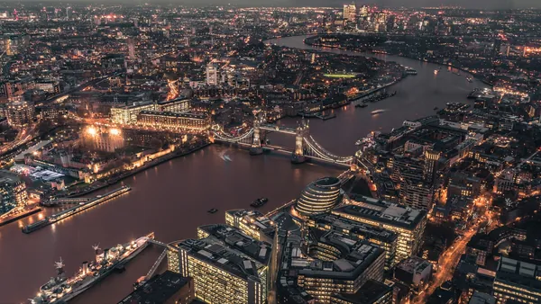 Vista aérea nocturna de Londres con el Tower Bridge iluminado cruzando el Támesis y la Torre de Londres en primer plano.