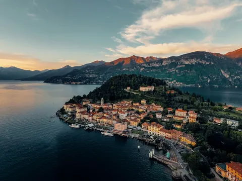 Vista aérea del Lago di Como al atardecer con pueblo costero y montañas