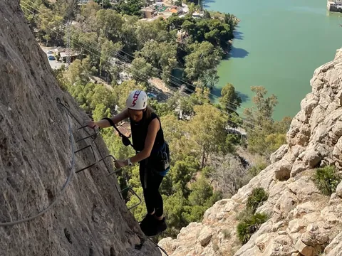 Mujer escalando en la vía ferrata Caminito del Rey frente al embalse