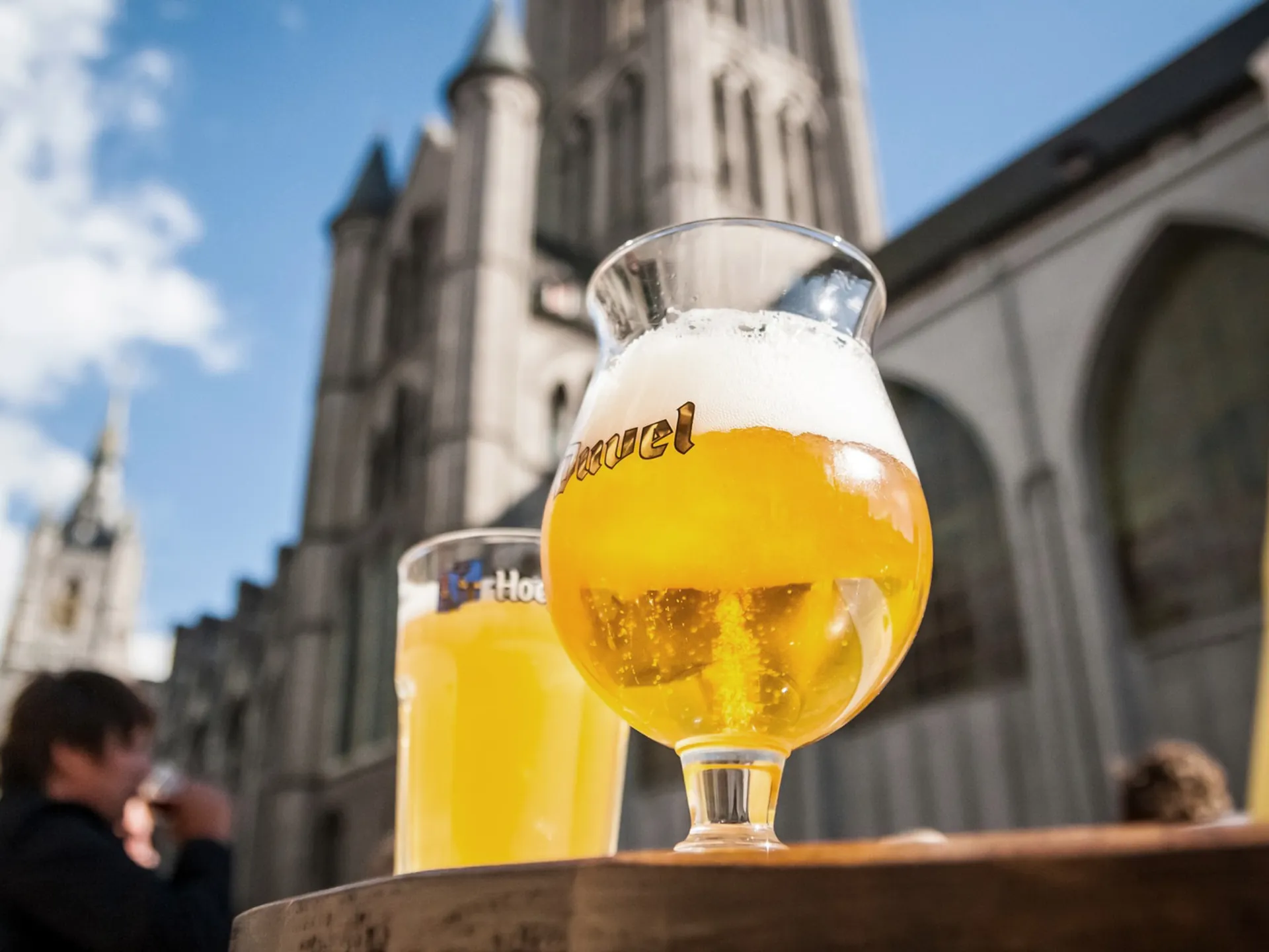 Copa de cerveza en una mesa, con edificios de fondo