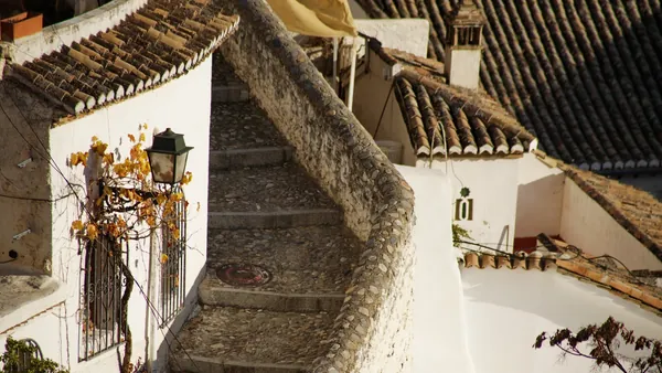 Callejuela empedrada con escaleras y casas blancas típicas del Albaicín, Granada